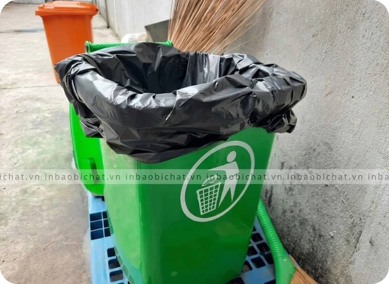 Túi rác công nghiệp được lồng trong thùng rác nhựa xanh chuyên dụng.